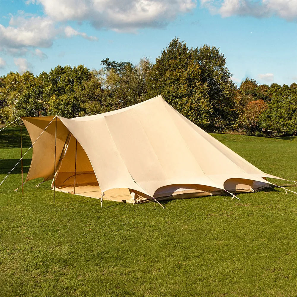 boutique camping tucana bell tent side view set up in a grassy field with trees in the background and blue skies