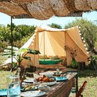 front view of the tucana tent with the front door open, the foreground features a table of sicilian food under a rattan canopy