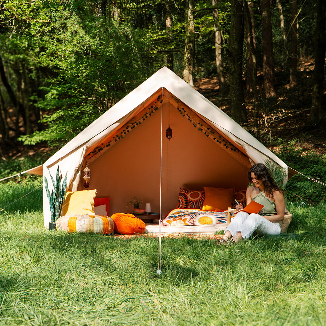 Spacious Vela Air Tent with bright orange cushions and natural wood accents – Perfect glamping setup from Boutique Camping