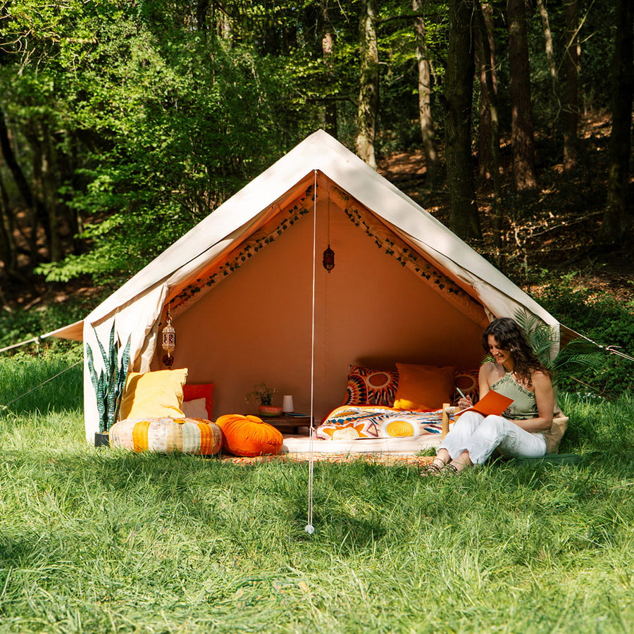 Spacious Vela Air Tent with bright orange cushions and natural wood accents – Perfect glamping setup from Boutique Camping