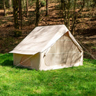 Vela Air Tent set up alone on a grassy field surrounded by trees, in bright natural light.