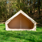 Vela Air Tent pitched in a wooded clearing, with the entrance open and framed by trees.